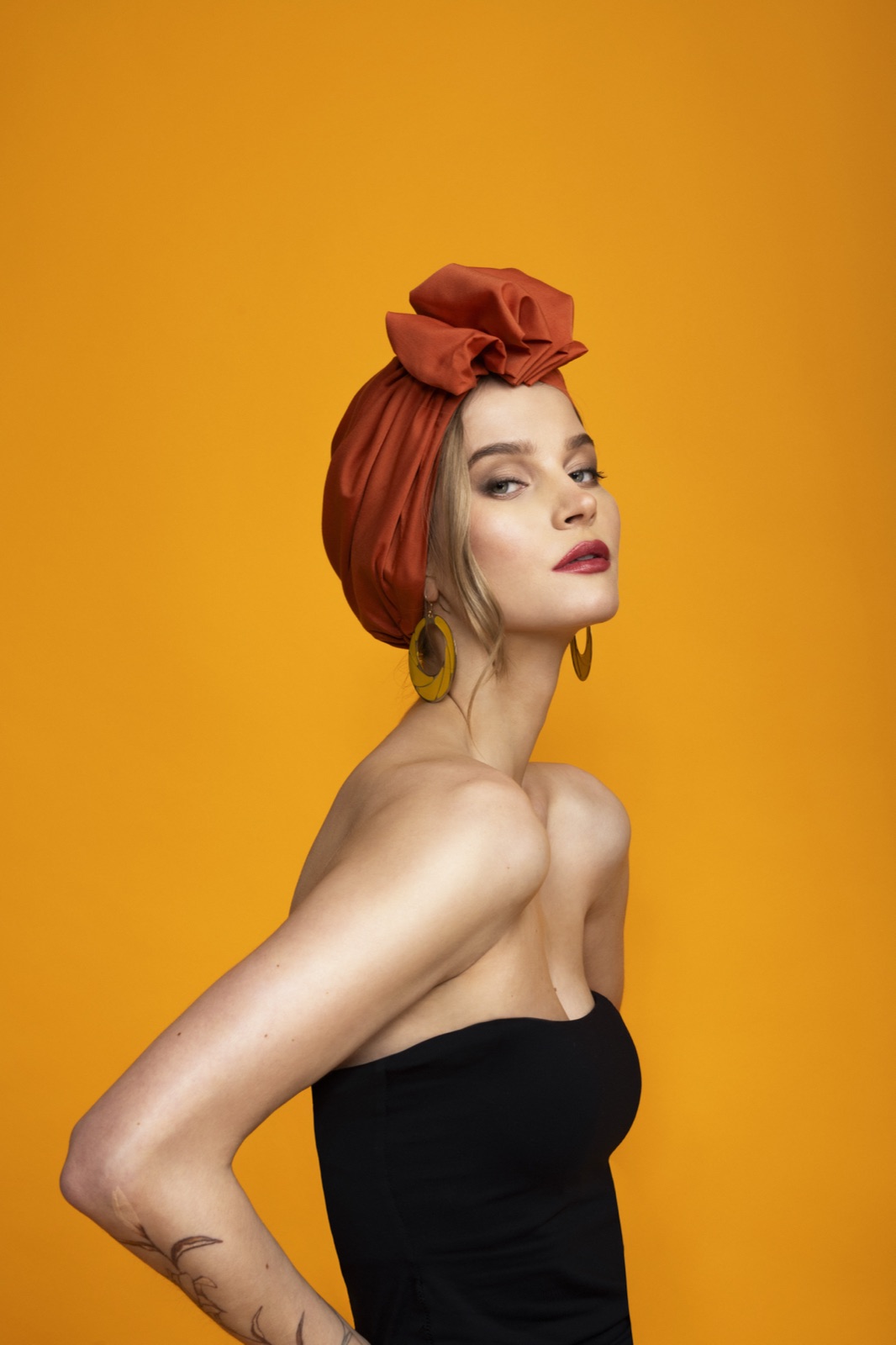 Model in profile wearing the Terracotta turban against a radiant marigold background